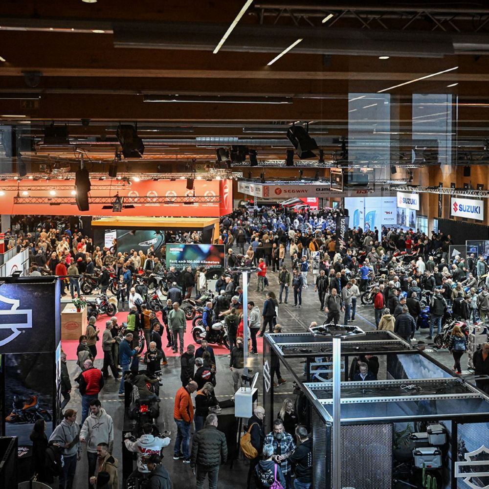 Preview moto-austria 2026 Blog I love my Moped - I love my moped Busy trade show floor with numerous booths, motorcycles on display, and attendees walking between exhibits.