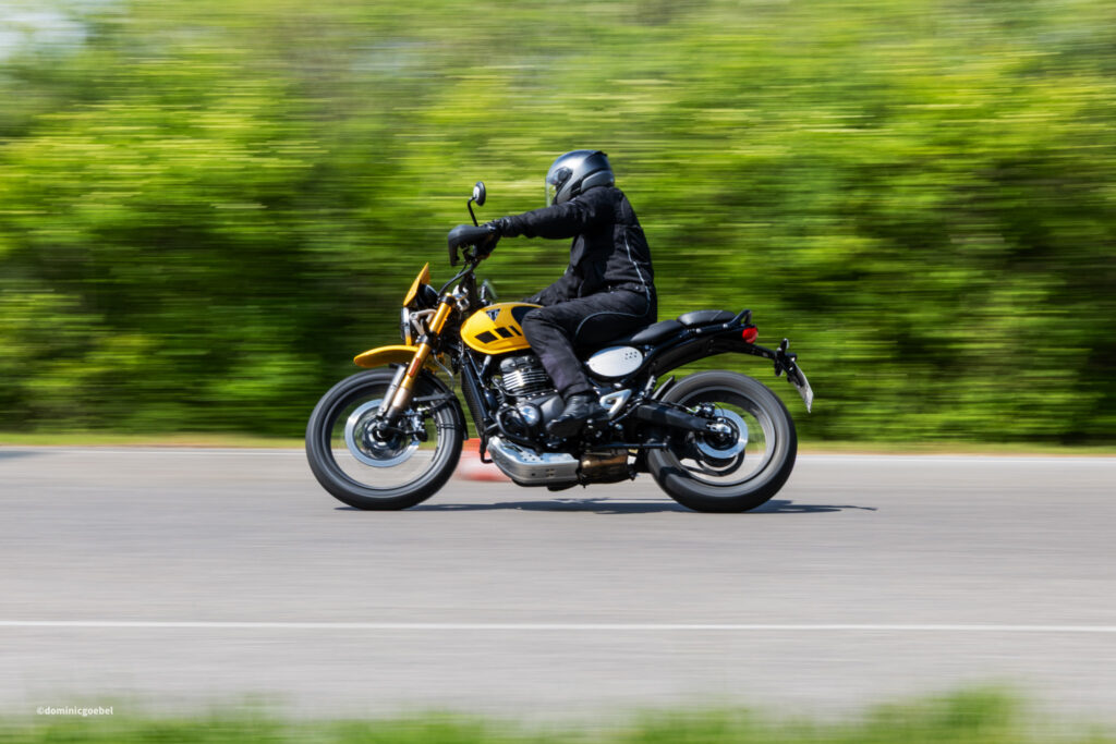 Motorrad Testtage 2026 Teesdorf c Dominic Goebel-12 - I love my moped Rider in helmet and black gear leaning forward on a yellow motorcycle as it speeds along a blurred green landscape background.