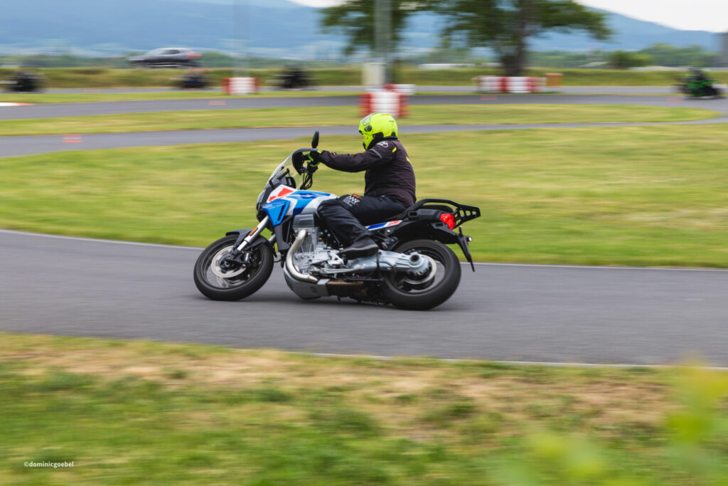 Motorrad Testtage 2026 Teesdorf c Dominic Goebel-29 - I love my moped Motorcyclist wearing a bright neon helmet leans into a turn on a racing track in motion blur.
