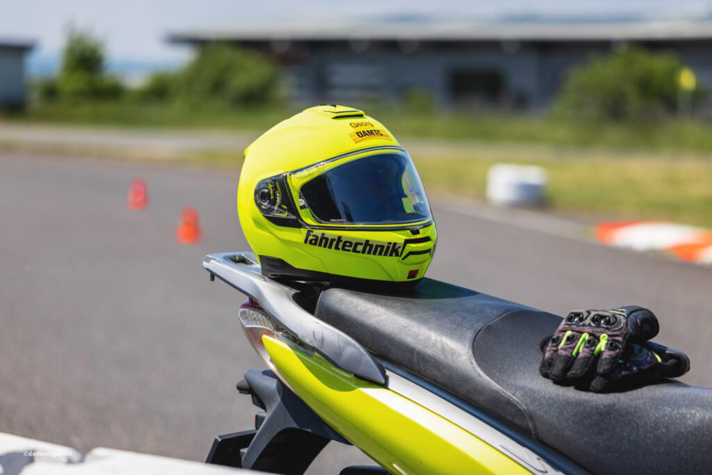 Motorrad Testtage 2026 Teesdorf c Dominic Goebel-43 - I love my moped Neon yellow motorcycle helmet with dark visor resting on a bike, outdoors on a sunny day.