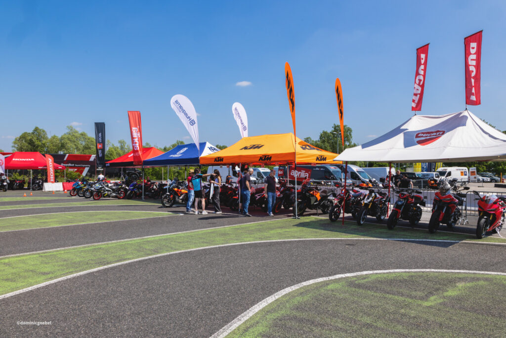 Motorrad Testtage 2026 Teesdorf c Dominic Goebel-44 - I love my moped Motorcycle event under colorful tents with KTM and Ducati banners; rows of bikes on display and people talking.