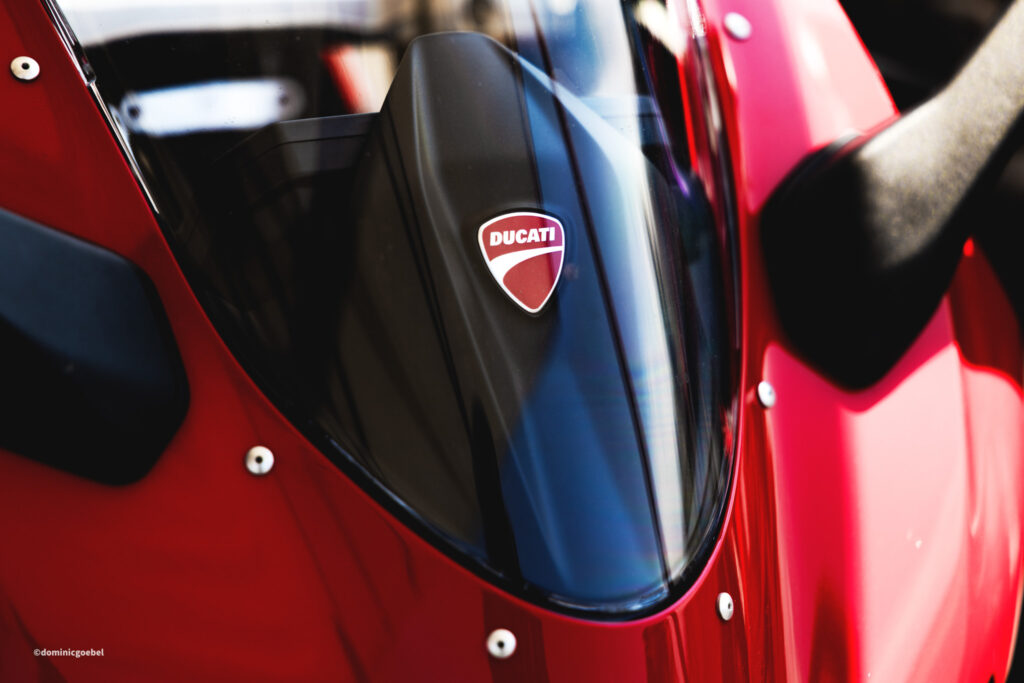 Motorrad Testtage 2026 Teesdorf c Dominic Goebel-7 - I love my moped Close-up of a red Ducati motorcycle fairing with a black panel displaying the Ducati shield emblem, glossy reflections visible on the surface.