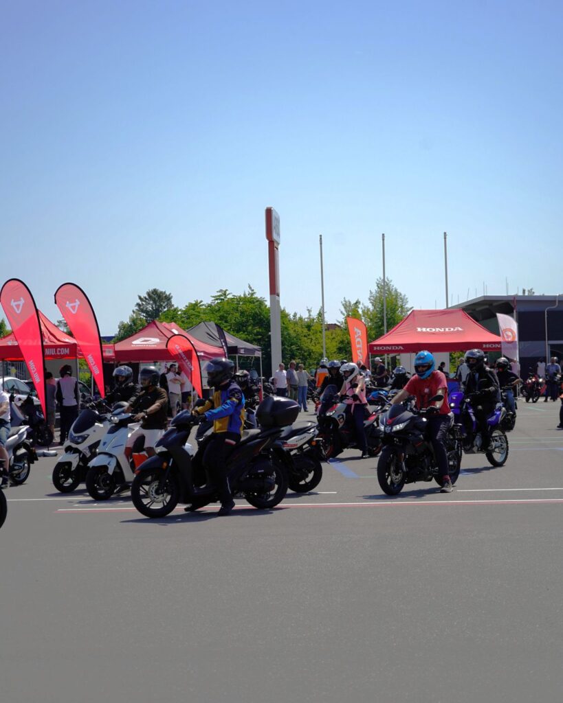 125er Testtag Arge 2Rad Wien 2026 - I love my moped group of motorcycle riders on a sunny day at a Honda-sponsored event with red tents and flags in the background