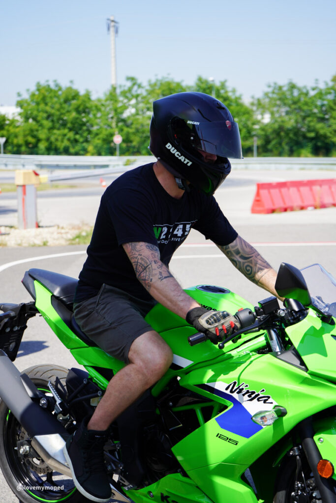 arge2rad-125ertesttag-arböfahrsicherheitszentrumwien-084 - I love my moped Rider wearing a black Ducati full-face helmet on a neon green Kawasaki Ninja 125 motorcycle on a track.
